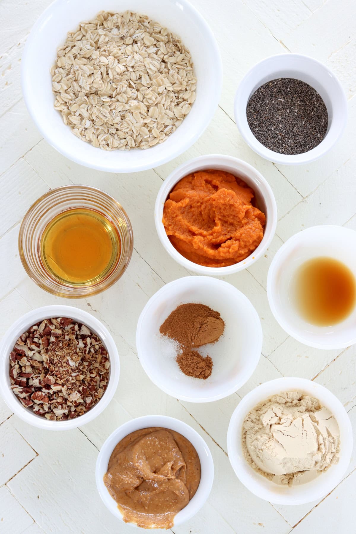 Ingredients needed for making pumpkin protein balls on a white wooden board.