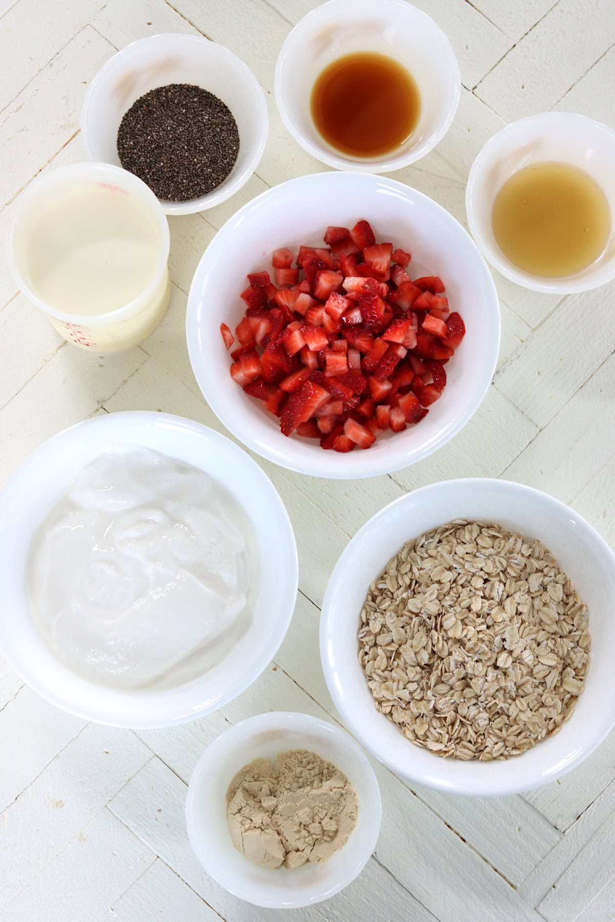 Ingredients needed for making overnight oats on a white wooden board.