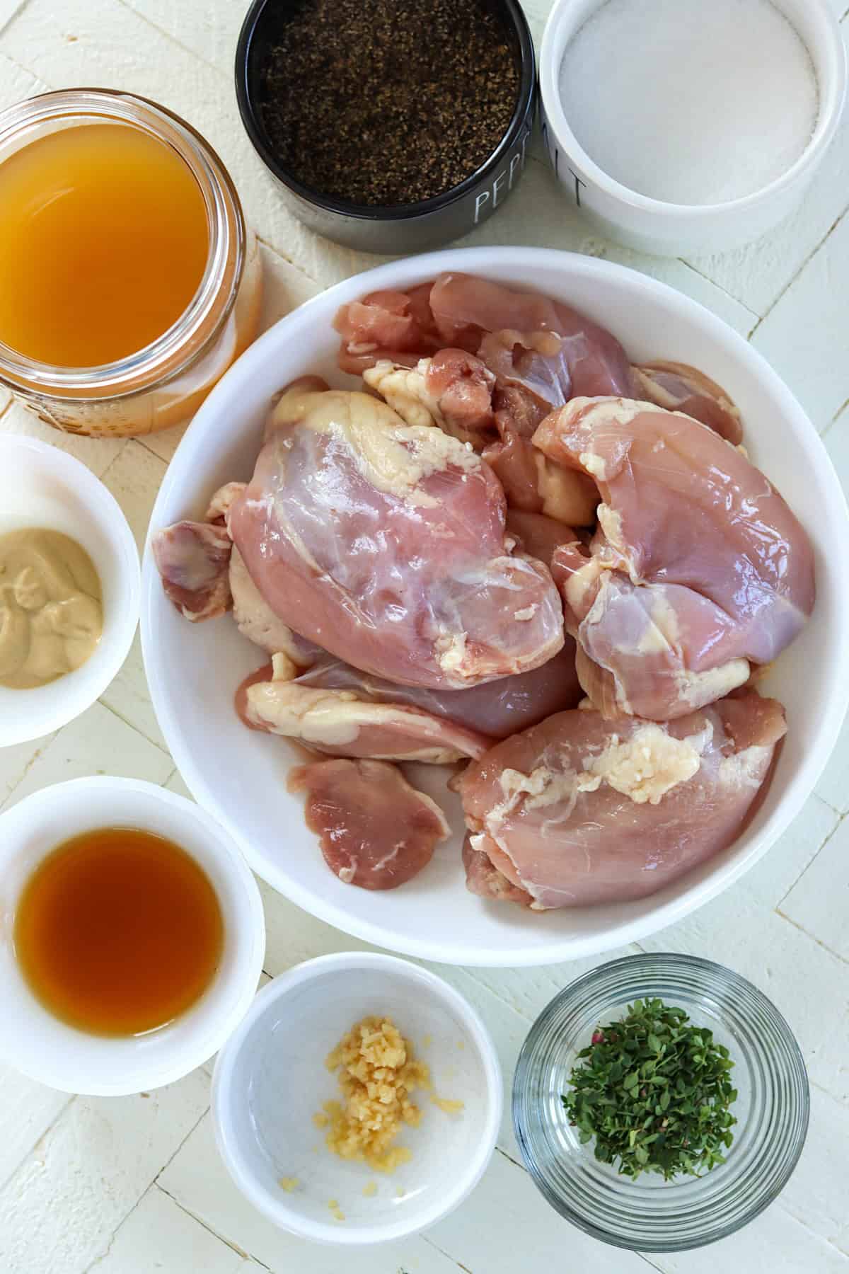 Ingredients needed for making glazed chicken thighs on a white wooded board.