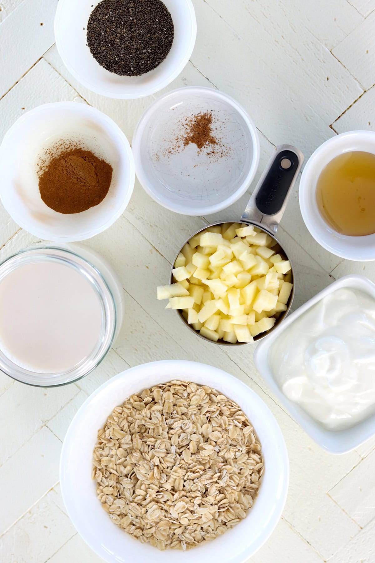 Overnight oats apple cinnamon ingredients on a white wooded board.