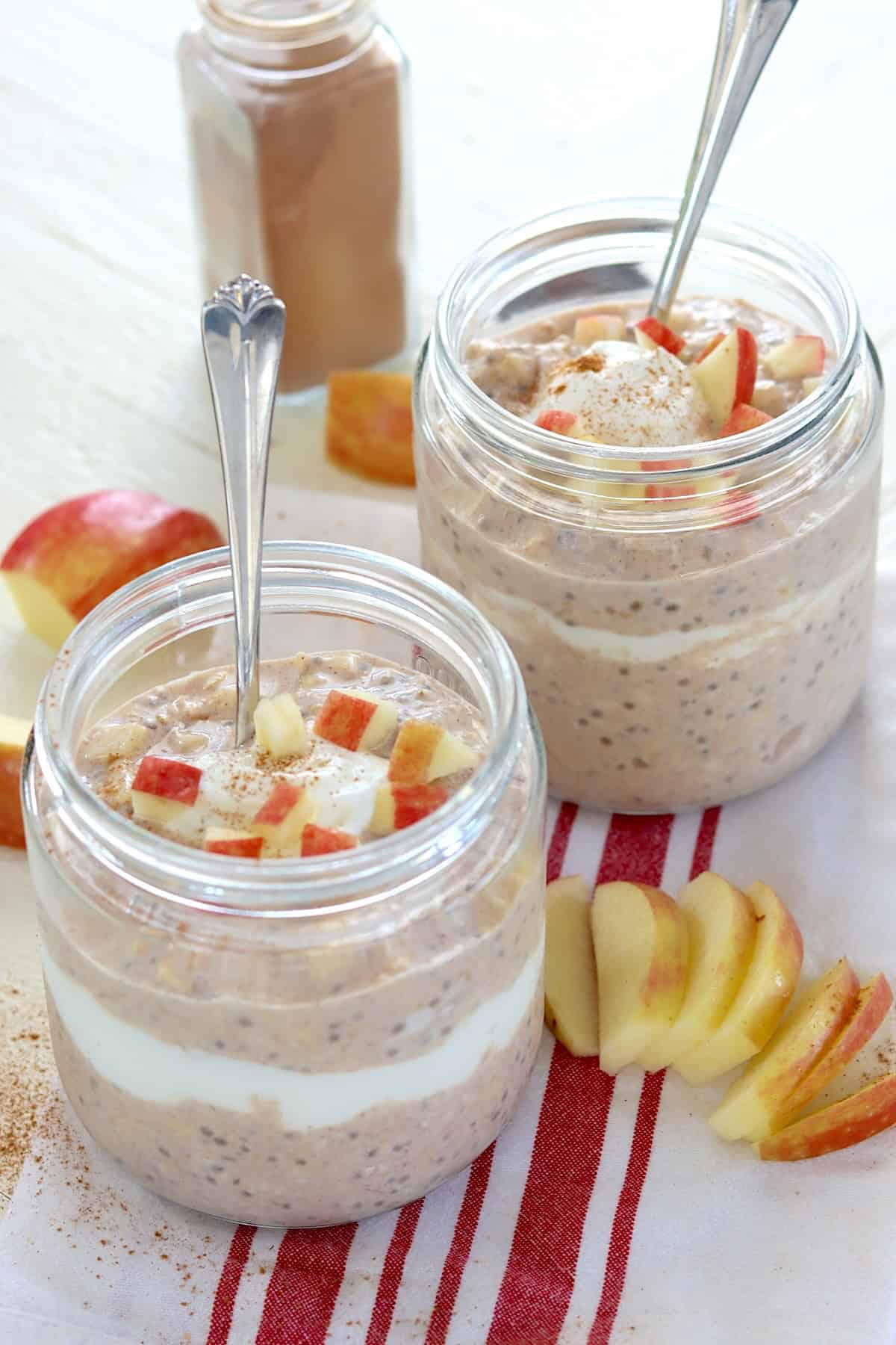 apple cinnamon overnight oats with sliced apples, a dollop of yogurt sprinkled with cinnamon.