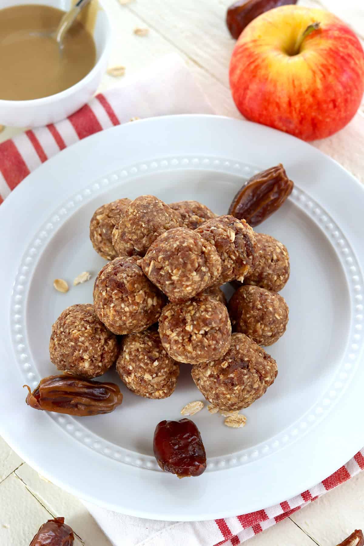 No bake energy bites with apples, tahini, oats, and dates piled on a white plate.