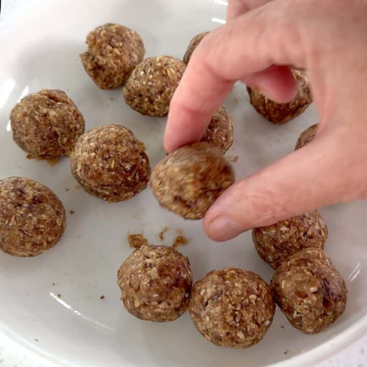 Shaping an oat energy bite and placing on a white plate.