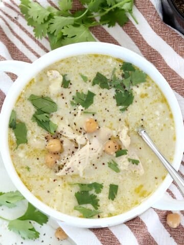 Healthy green chicken enchilada soup in a white bowl with chickpeas and cilantro.