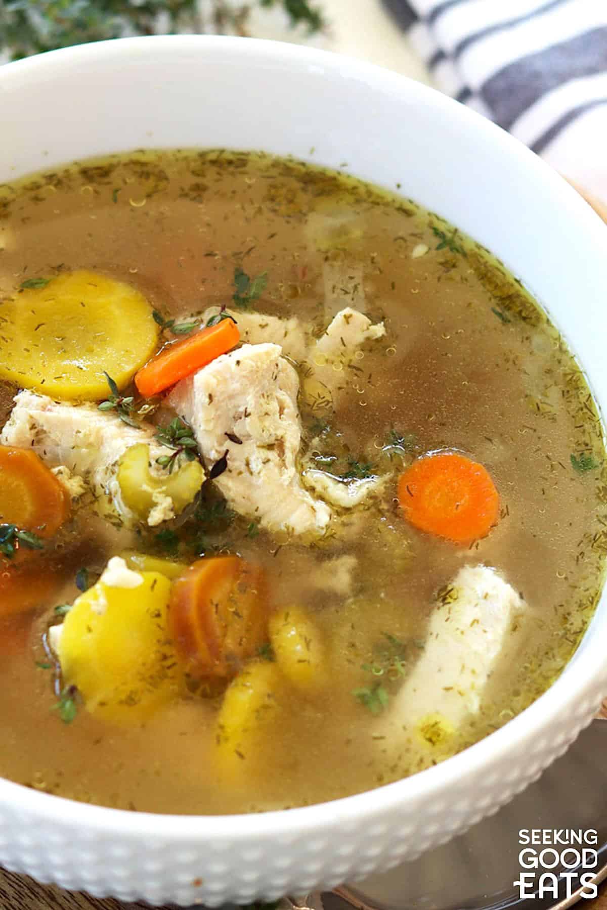 Instant pot chicken soup in a white bowl with colorful carrots.