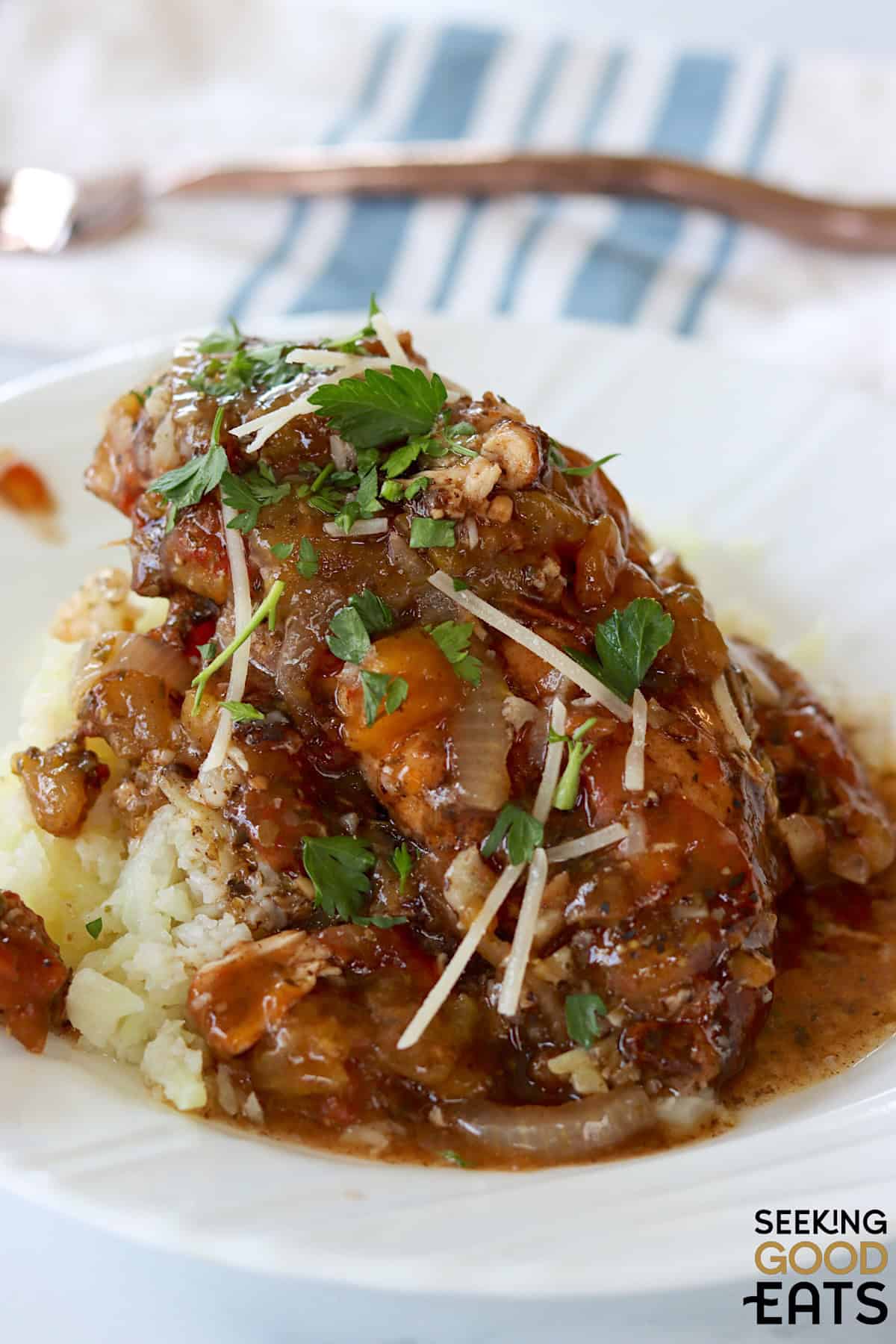 Slow cooker balsamic chicken served over riced cauliflower on a white plate.