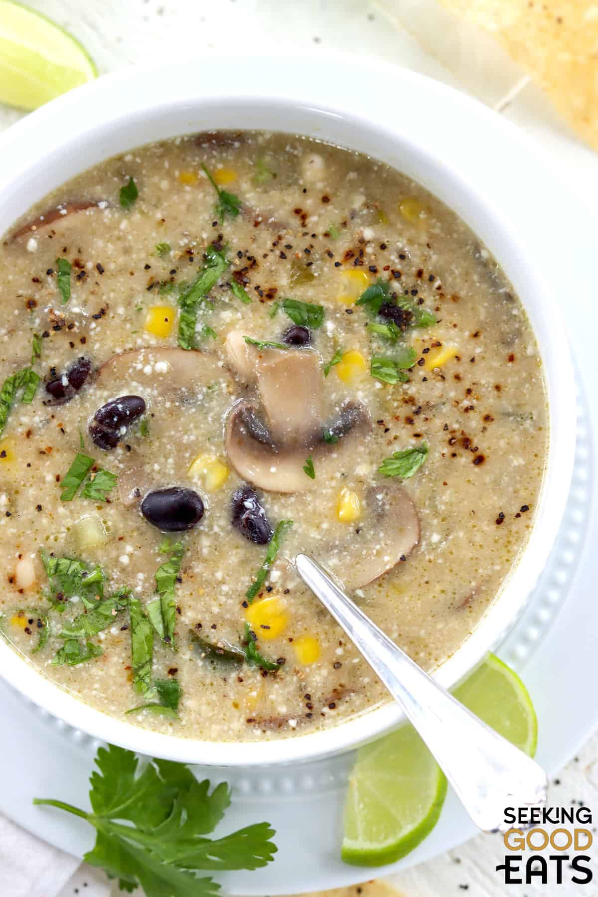 Vegan white bean enchilada soup with green enchilada sauce and silken tofu in a white bowl.