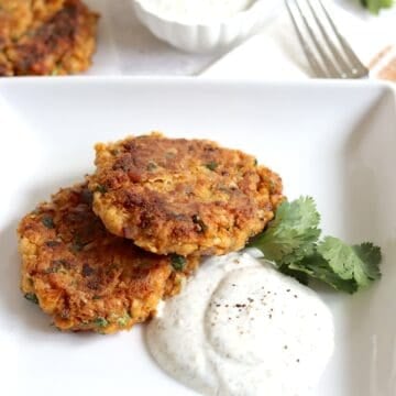Chickpea fritters on a white square plate and dipping sauce on the side.