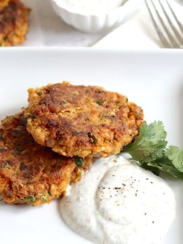 Chickpea fritters on a white square plate and dipping sauce on the side.