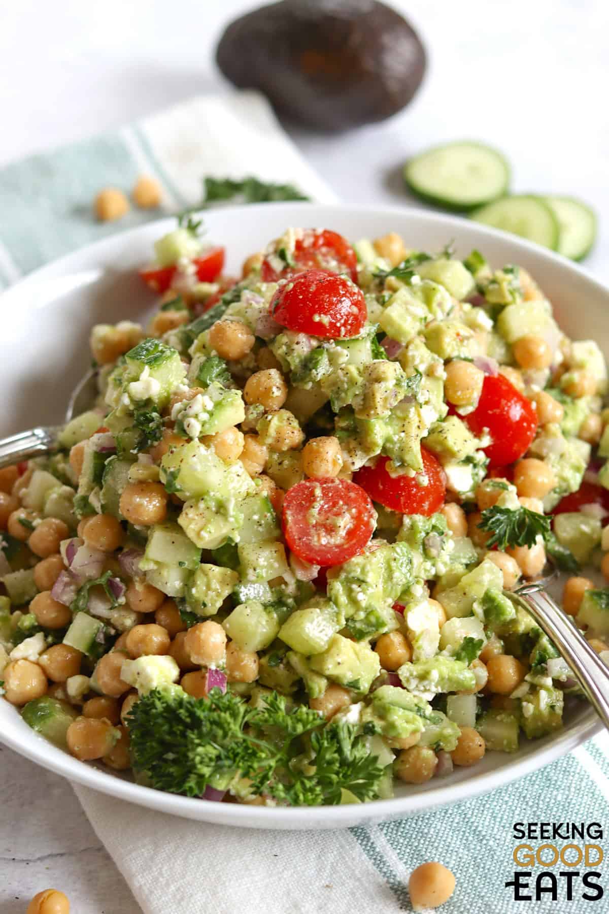 Feta avocado chickpea salad in a white bowl with two serving spoons.