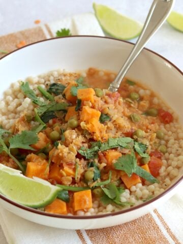 Sweet potato red lentil curry recipe in a white serving bowl and silver spoon.