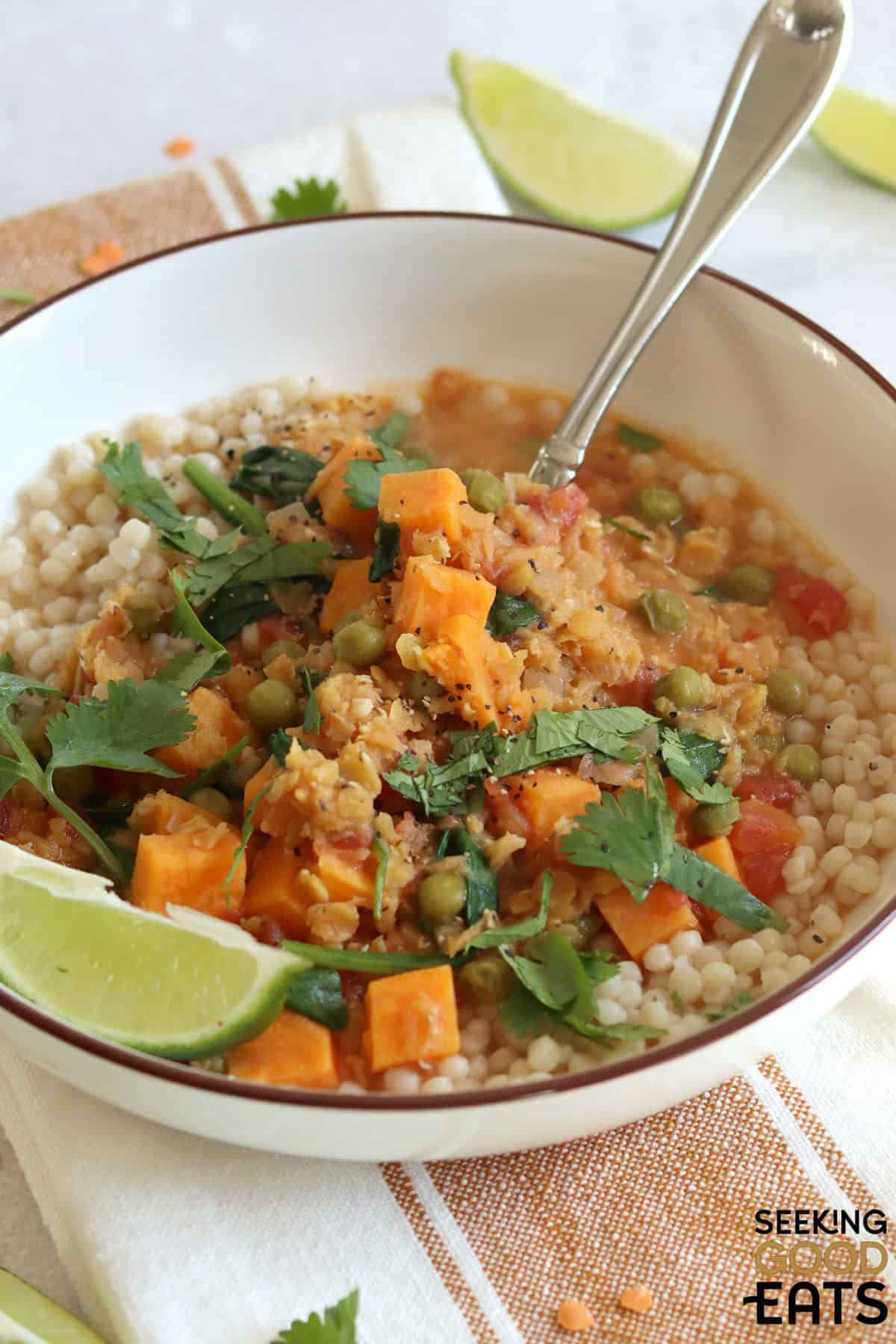 Sweet potato red lentil curry recipe in a white bowl with a silver spoon.
