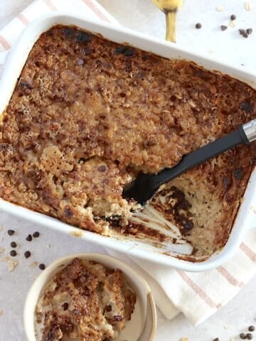 Banana chocolate chip baked oatmeal in a rectangle white pan and black serving spoon.