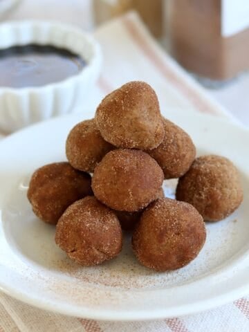 No bake gingerbread protein bites stacked on a white round plate.