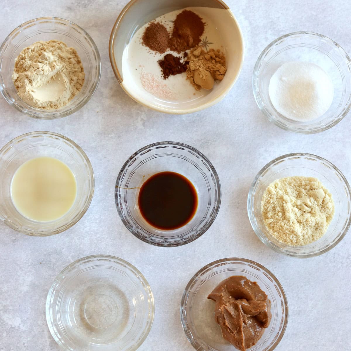 Ingredients needed to make no bake gingerbread protein bites on a white marble countertop.