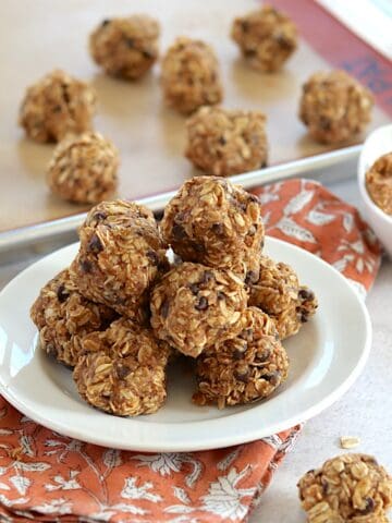 No bake oatmeal and peanut butter balls stacked on a white round plate.