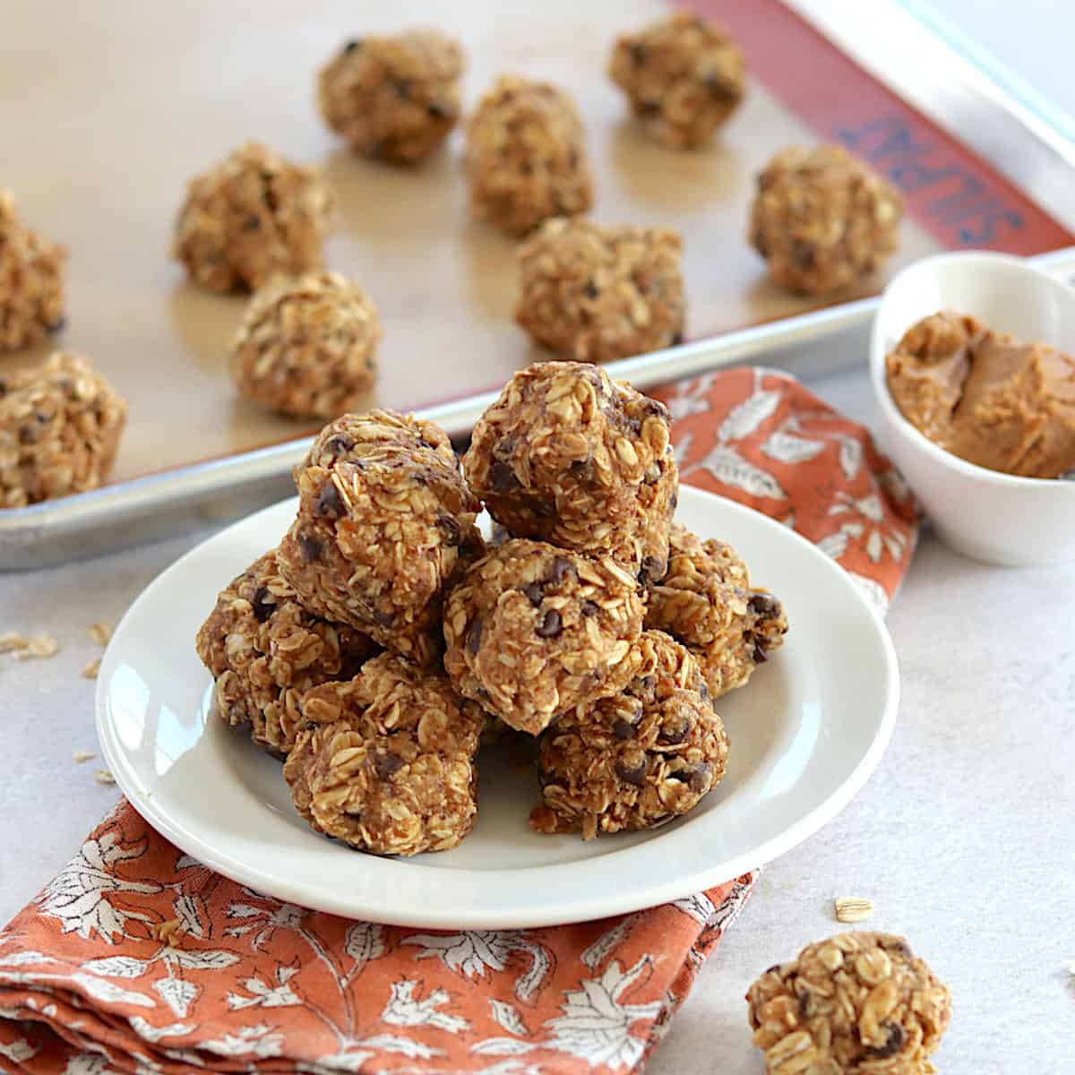No bake oatmeal and peanut butter balls stacked on a white round plate.