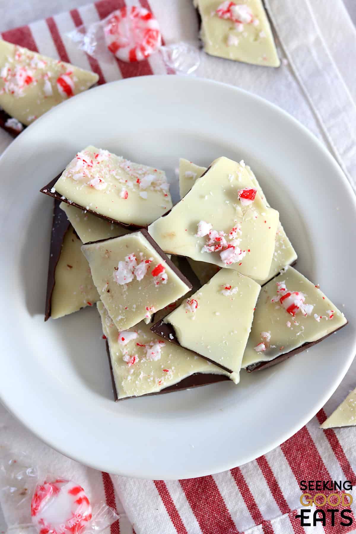 Pieces of sugar free peppermint bark piled on a white round plate.