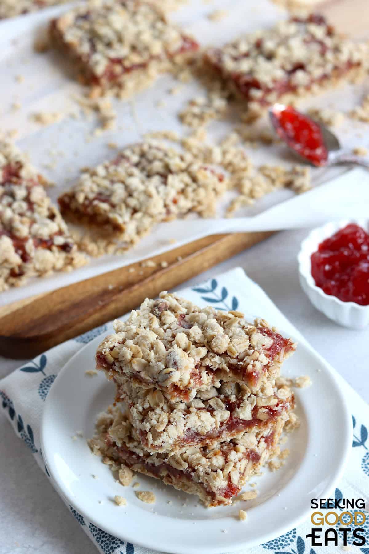 Strawberry oatmeal bars cut into squares, and three stacked on a small white plate.
