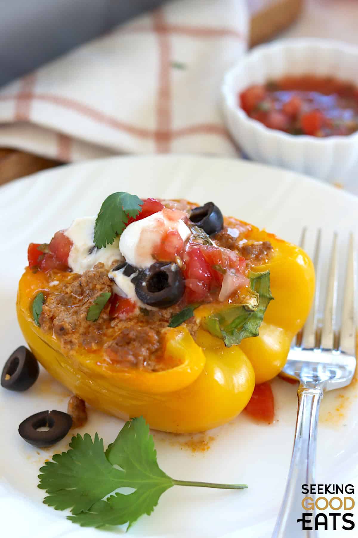 Yellow taco stuffed bell peppers garnished with sour cream and salsa.