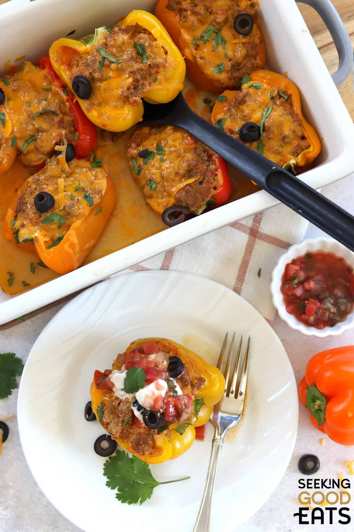 A white plate and baking dish of taco stuffed bell peppers.
