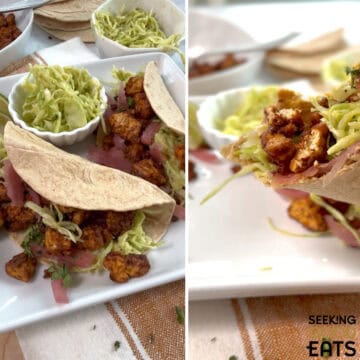 Two tofu tacos on a white square plate with a small round bowl of slaw on the plate. Taking a bite out of the tofu taco and seeing the layers of tofu, slaw and pickled onion on the taco.