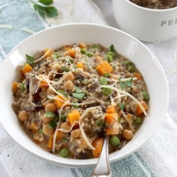 Savory oatmeal with mushroom and sweet potatoes in a white round bowl and a silver spoon.