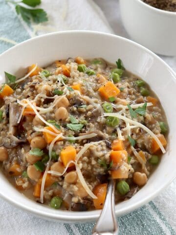 Savory oatmeal with mushroom and sweet potatoes in a white round bowl and a silver spoon.