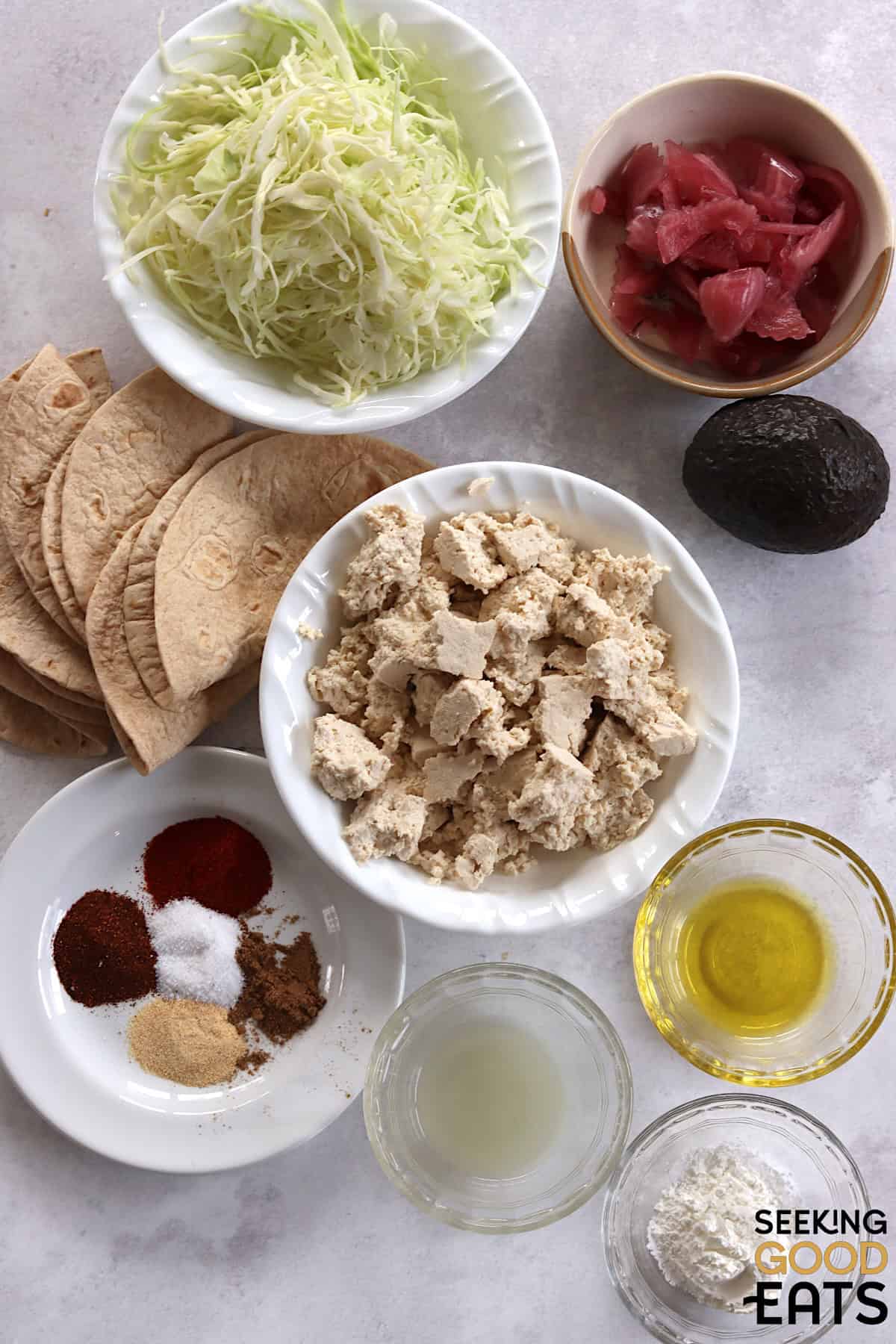 Ingredients needed to make tofu tacos arranged on a marble white countertop.