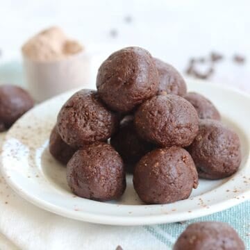 Easy protein brownie balls stacked on a white round plate.