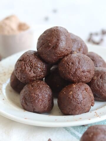 Easy protein brownie balls stacked on a white round plate.