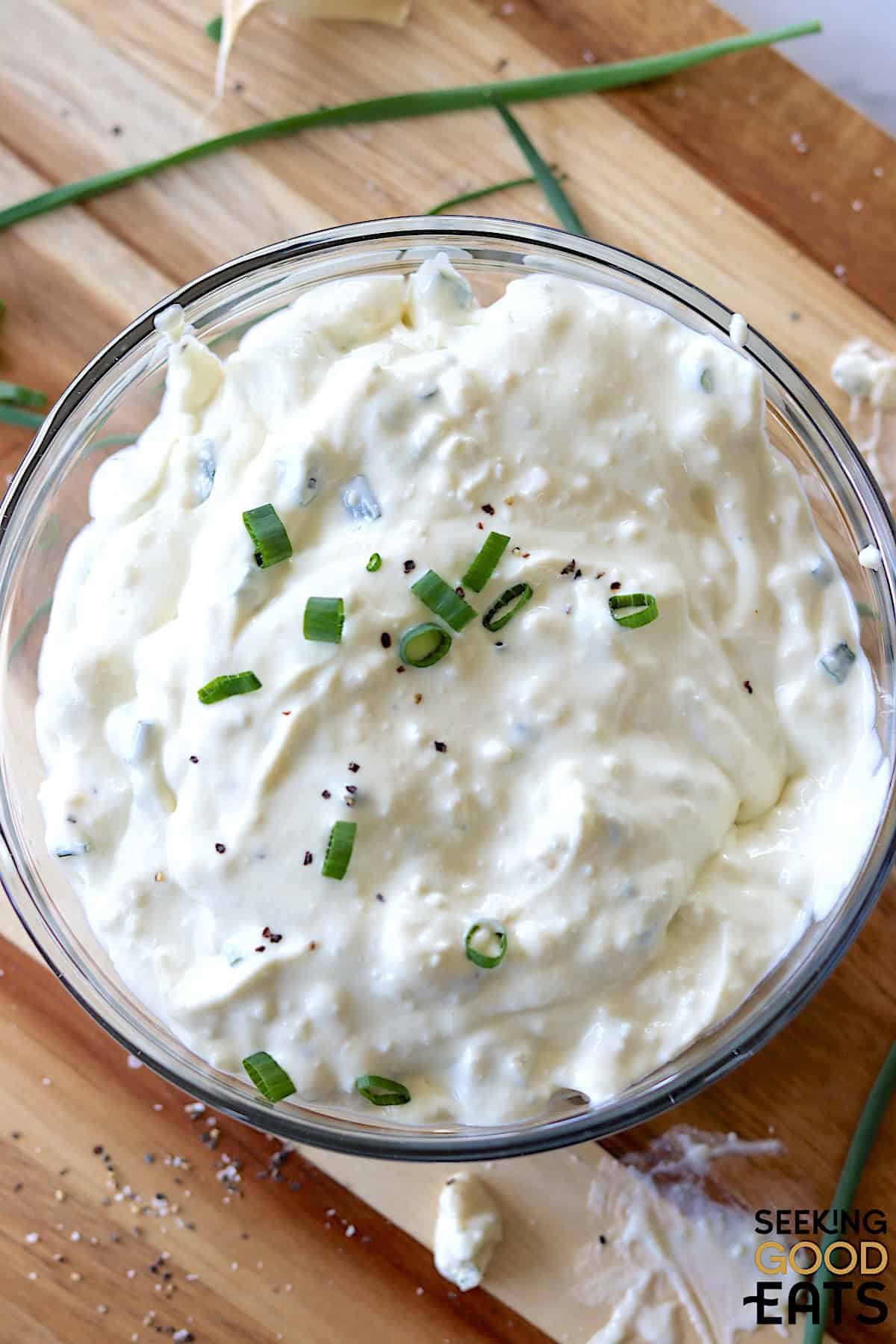 A clear glass bowl of chunky blue cheese dressing.