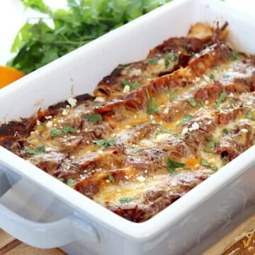 Steak enchiladas recipe in a gray baking dish with cilantro.