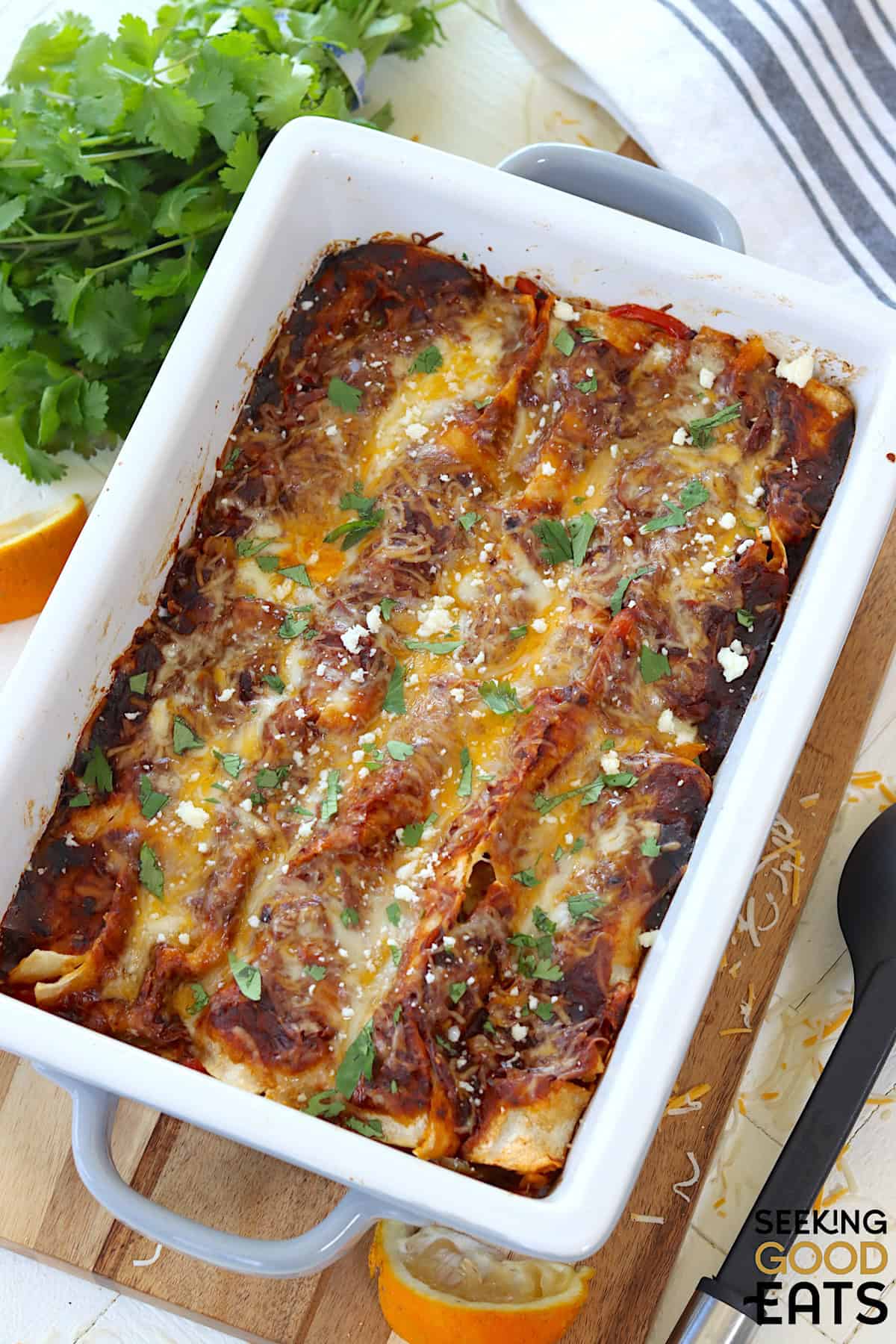 Steak and cheese enchiladas in a white casserole dish.