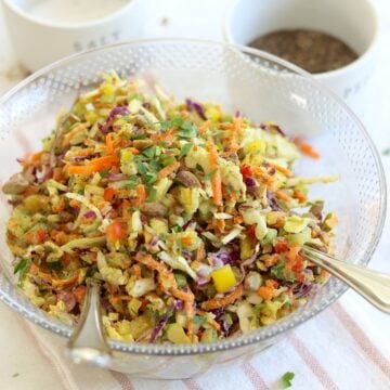 Green goddess cabbage salad served in a clear bowl and two silver serving spoons.