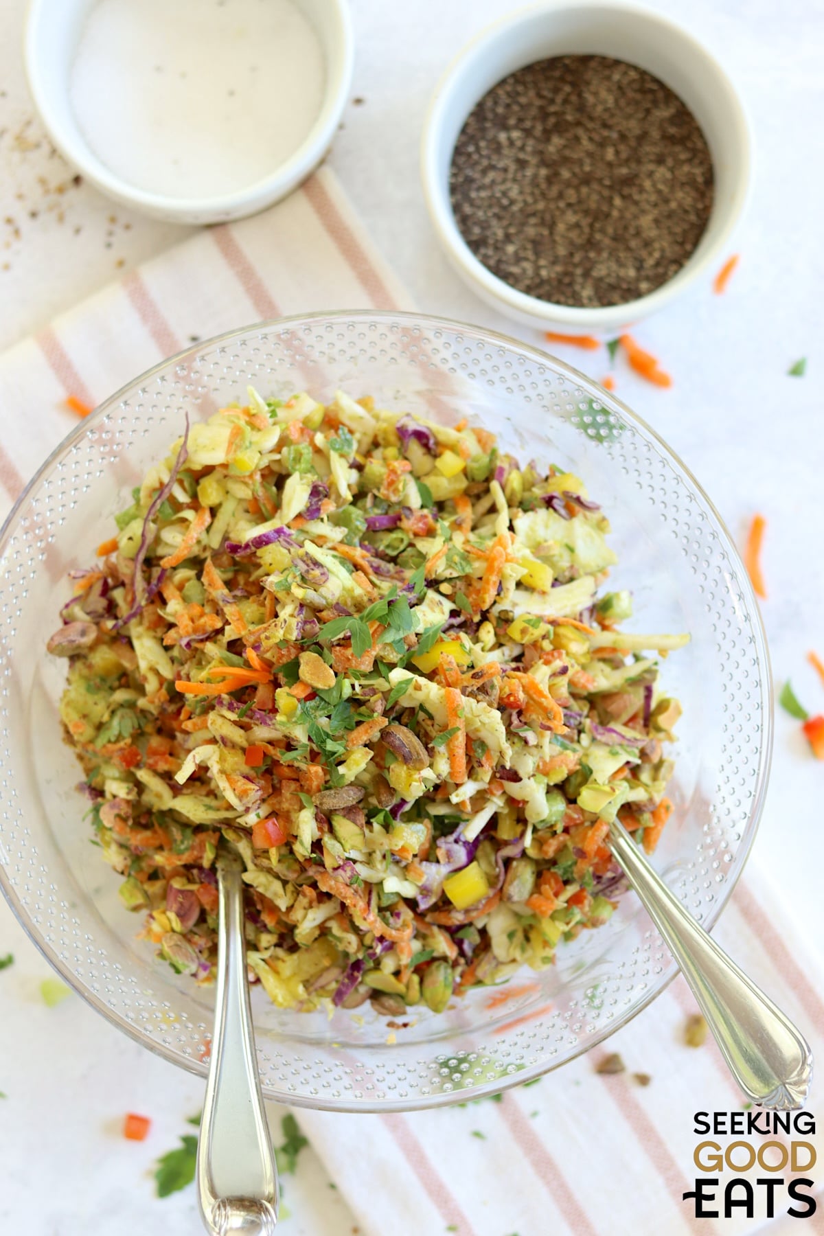 Green goddess cabbage salad served in a large clear bowl and two silver serving spoons.