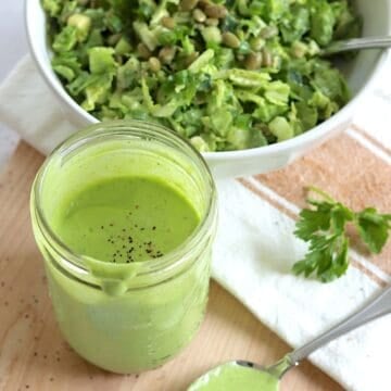 Green goddess dressing recipe served in a clear mason jar, topped with a sprinkle of black pepper.