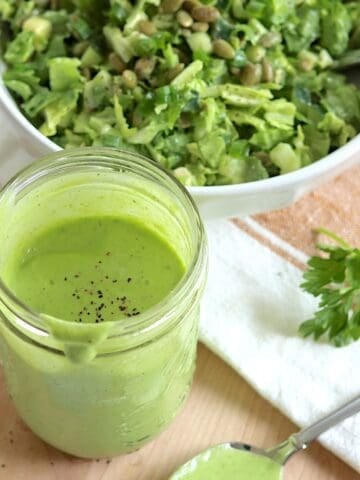 Green goddess dressing recipe served in a clear mason jar, topped with a sprinkle of black pepper.