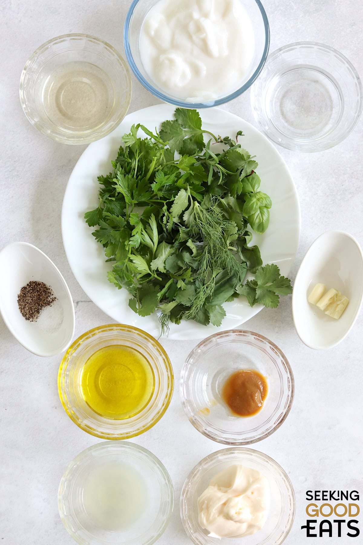 Ingredients needed to make green goddess dressing recipe on a white marble countertop.