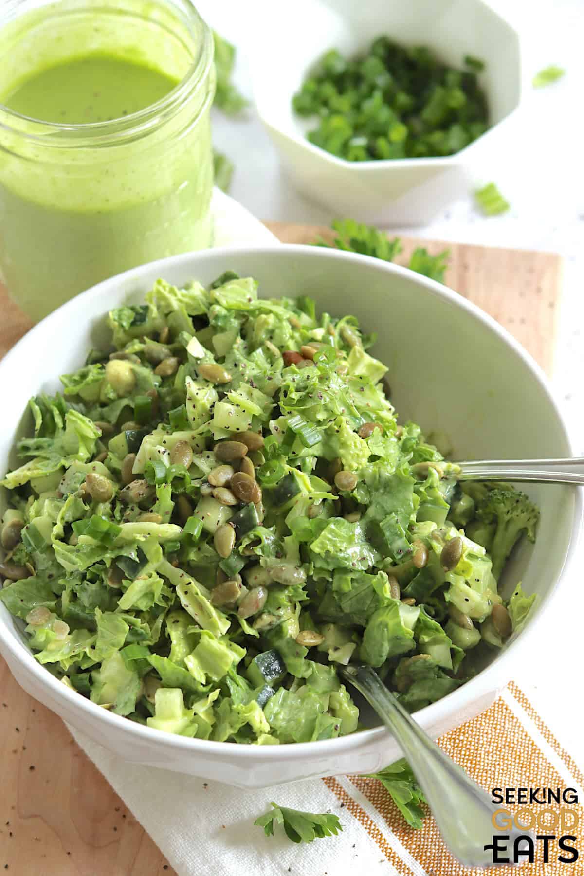 Green goddess salad recipe served in a white round bowl and two silver serving forks.