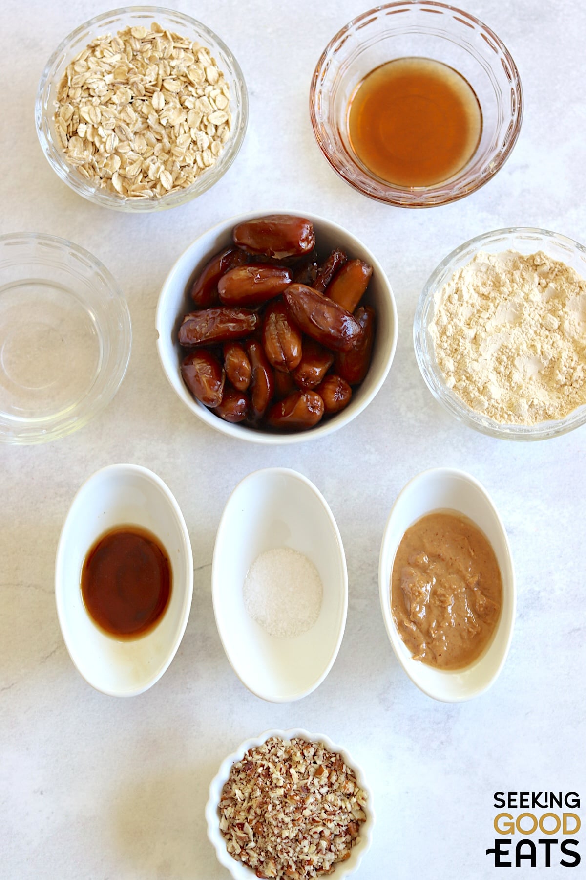 Ingredients needed to make date protein balls arranged on a white marble countertop.