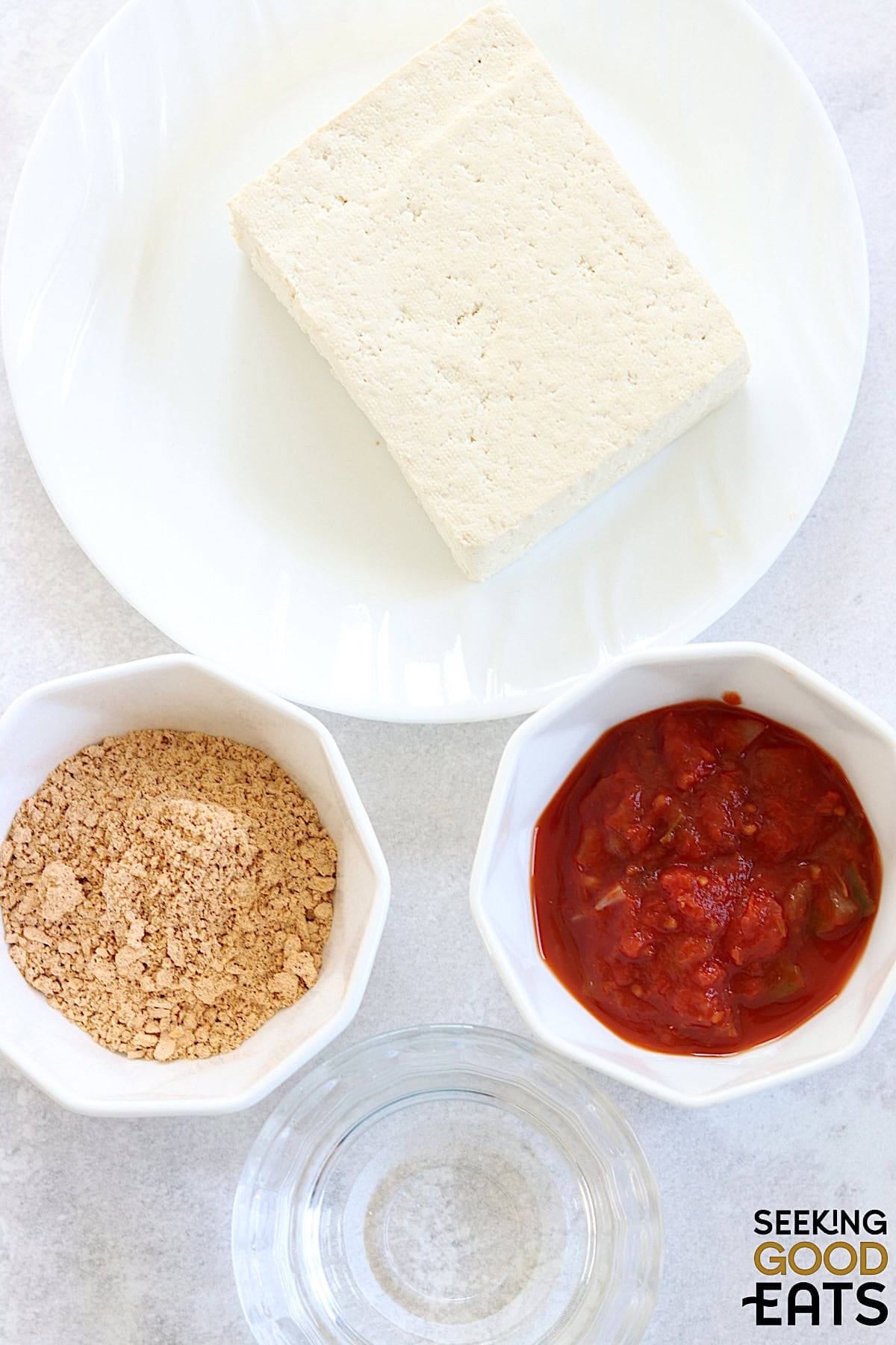 Ingredients needed to make plant based tofu taco meat on a white marble countertop.