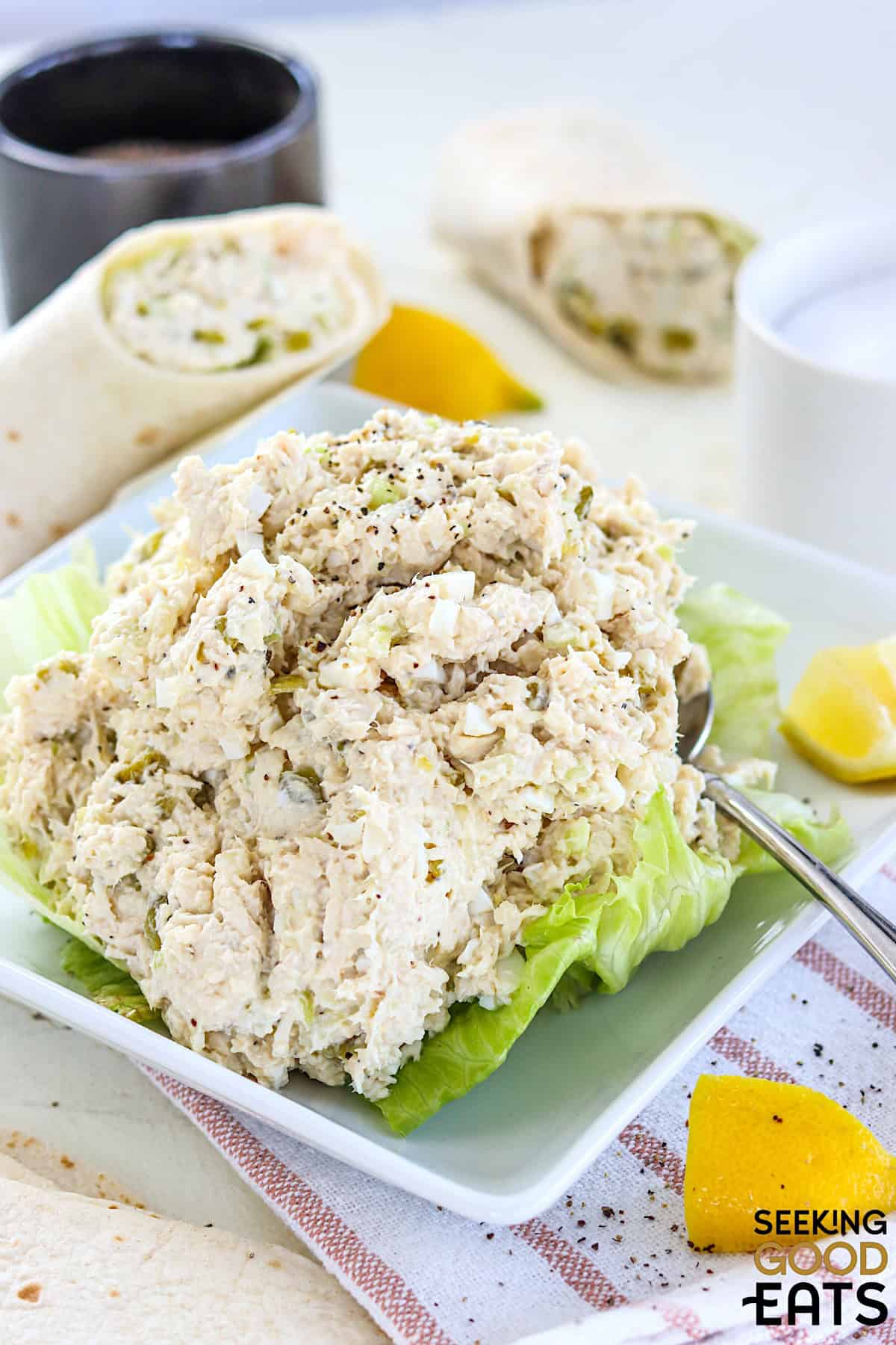 Chicken salad chick fil a copycat recipe on a white plate with lettuce and a side of lemon wedges.