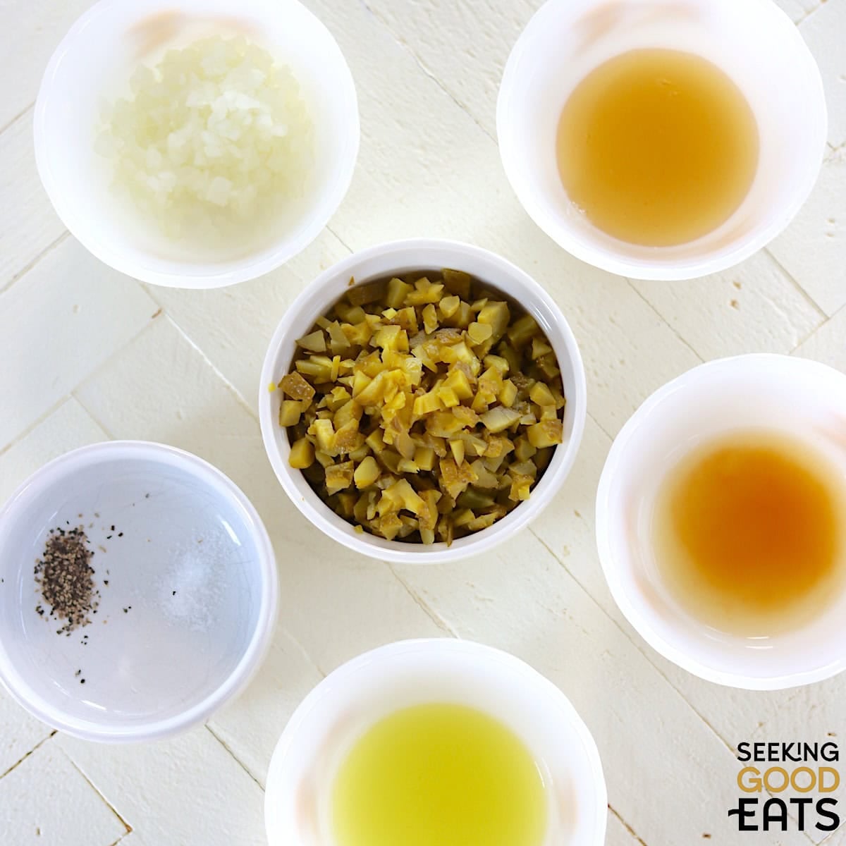 Ingredients needed to make dill pickle relish arranged on a white countertop.