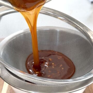 Straining the hot honey through a sieve