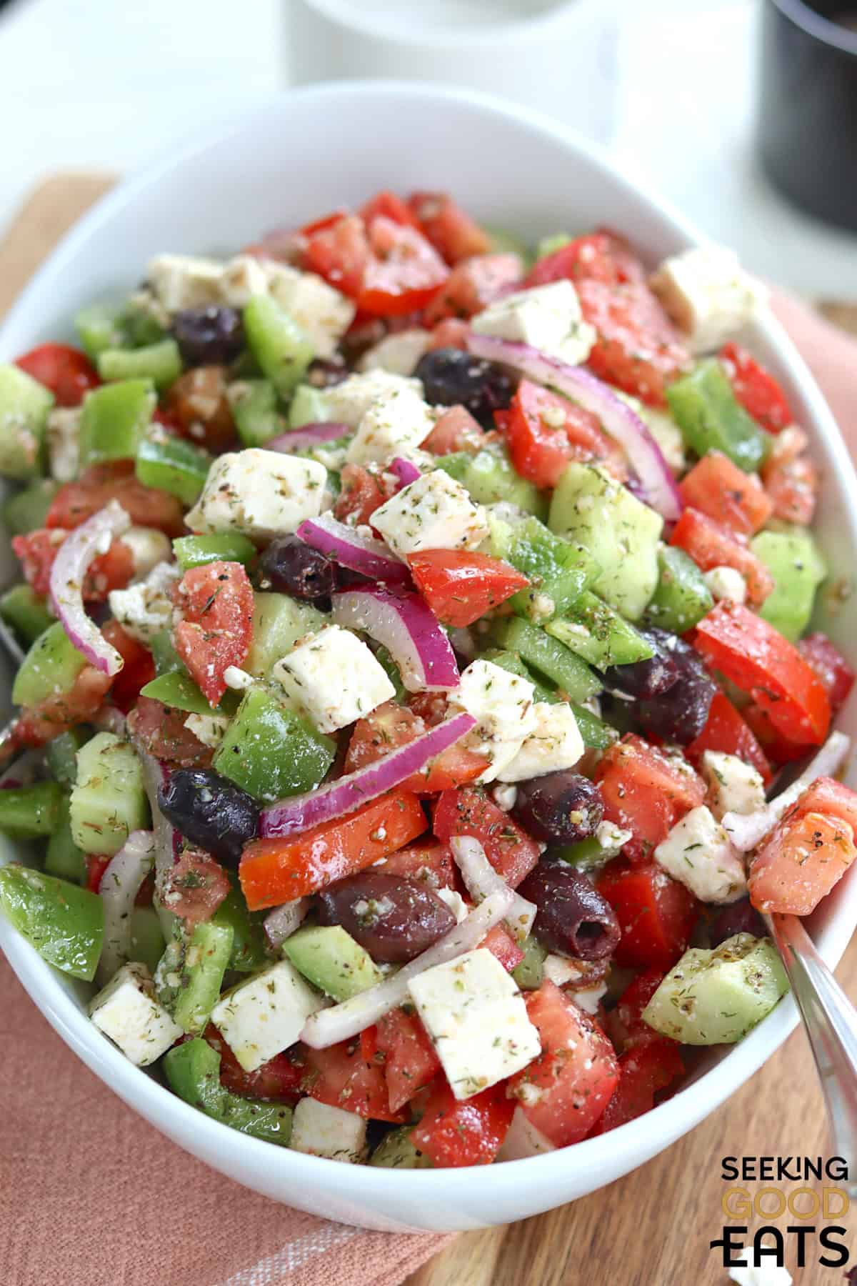 colorful and vibrant Greek salad recipe in a white bowl.