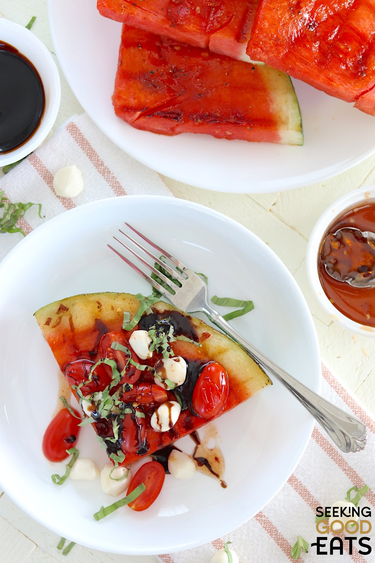 A wedge of grilled watermelon caprese salad on a white plate.
