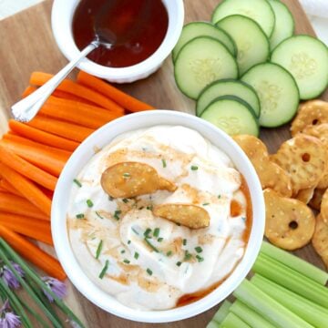A wooded board with a bowl of whipped cottage cheese dip with hot honey.