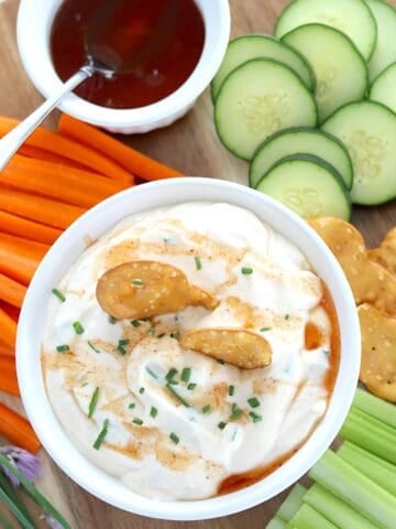 A wooded board with a bowl of whipped cottage cheese dip with hot honey.