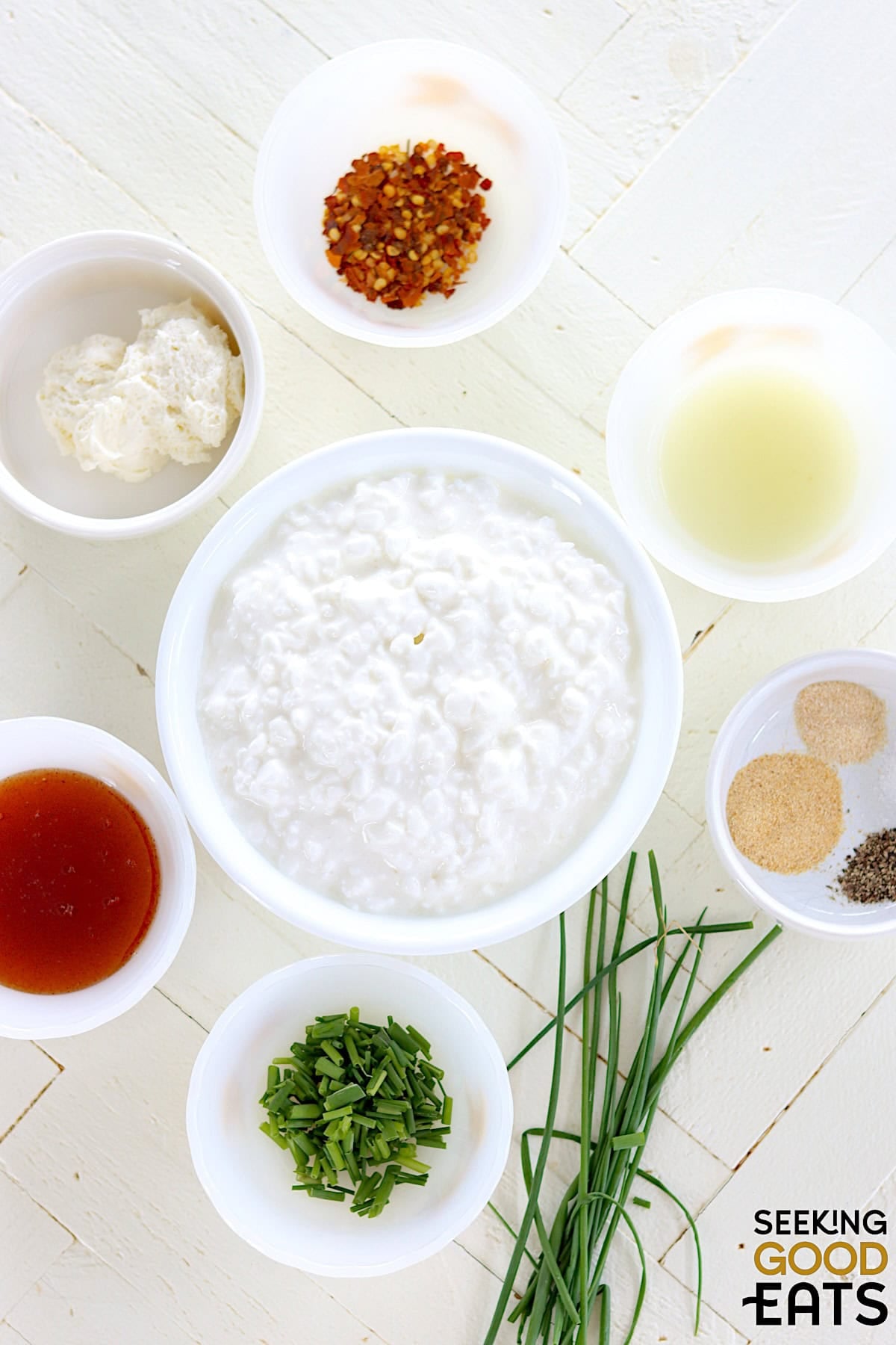 Ingredients needed for making hot honey whipped cottage cheese dip on a white wooded board.